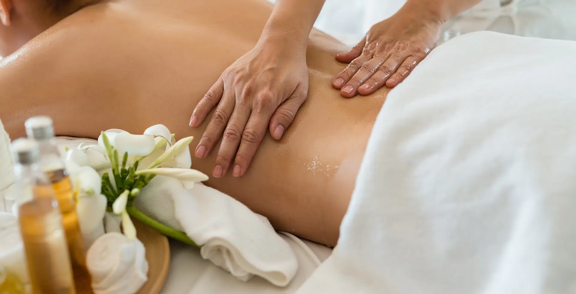 Massage du dos avec huiles et fleurs blanches